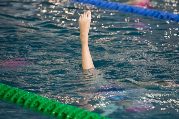 Nadadores sincronizados apontam para fora da água em ação. Movimento sincronizado das pernas dos nadadores. Equipe de natação sincronizada executando uma rotina sincronizada de movimentos elaborados na água . — Fotografia de Stock