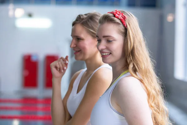 Swim coach blowing whistle and looking at stopwatch near poolside.