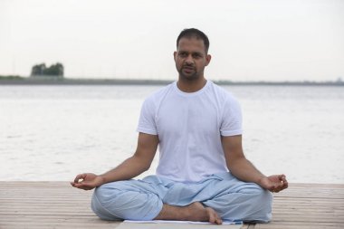 Fitness, spor, yoga ve sağlıklı yaşam konsepti - kadar yakın insan kolay oturma poz nehir ya da göl rıhtım üzerinde meditasyon
