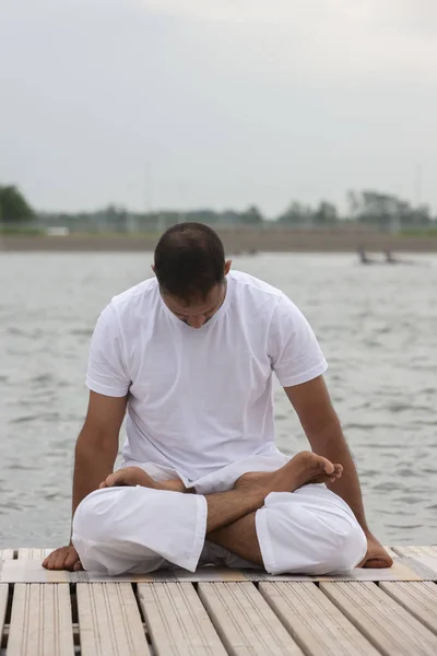 Young man doing yoga and meditating in warrior pose on beach — Stock Photo, Image