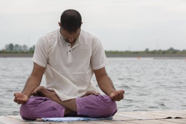 Genç adam yoga yapıyor ve savaşçı sahilde poz meditasyon
