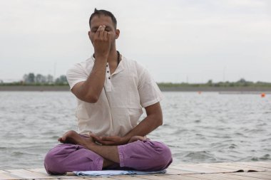 Genç adam yoga yapıyor ve savaşçı sahilde poz meditasyon