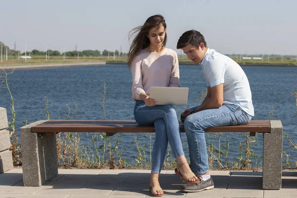 Hombre y mujer utilizando el ordenador portátil al aire libre. Imagen de pareja joven hombre y mujer en ropa casual . — Foto de Stock
