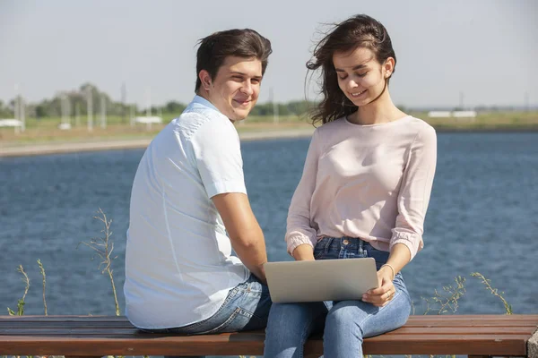Homem e mulher usando laptop ao ar livre. Imagem de jovem casal homem e mulher em roupas casuais . — Fotografia de Stock
