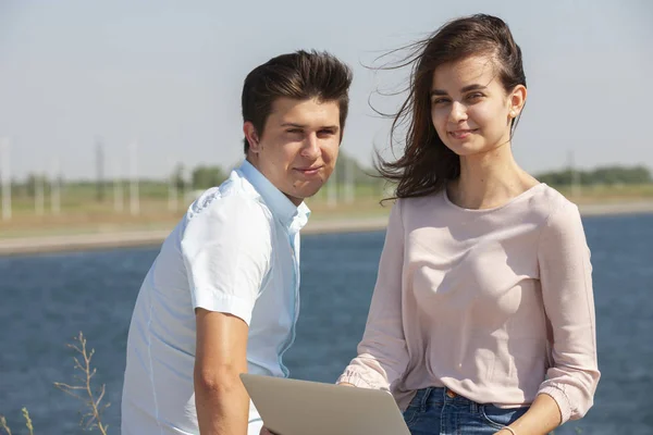 Homem e mulher usando laptop ao ar livre. Imagem de jovem casal homem e mulher em roupas casuais . — Fotografia de Stock