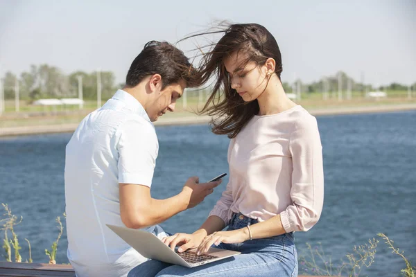男人和女人在户外使用笔记本电脑。年轻夫妇的男女在休闲服装的形象. — 图库照片