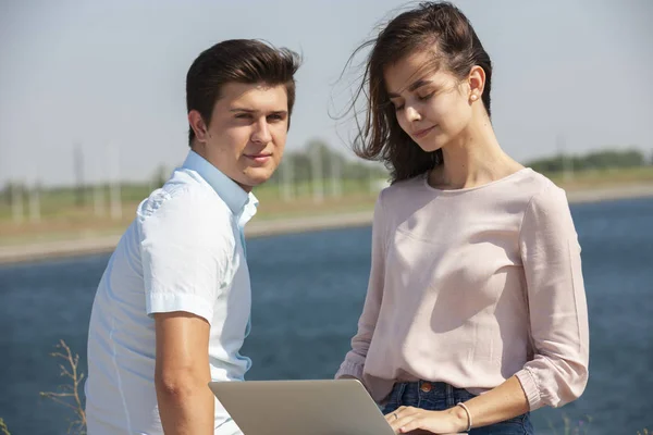 Hombre y mujer utilizando el ordenador portátil al aire libre. Imagen de pareja joven hombre y mujer en ropa casual . — Foto de Stock