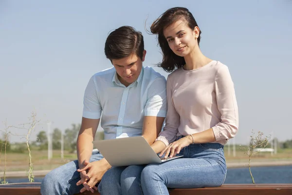 Pareja usando un ordenador portátil al aire libre y mirando feliz —  Fotos de Stock