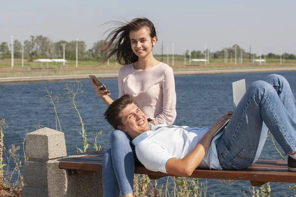Mutlu genç çift birlikte parkta otururken dizüstü bilgisayar kullanarak — Stok fotoğraf
