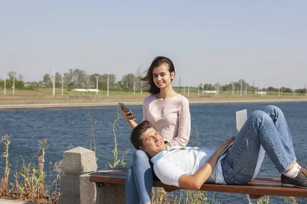 快乐的年轻夫妇使用笔记本电脑, 而坐在一起在公园 — 图库照片