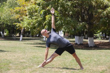 Parkta egzersiz eden adam. Gülümseyen beyaz erkek çim üzerinde çekirdek egzersiz yapıyor.