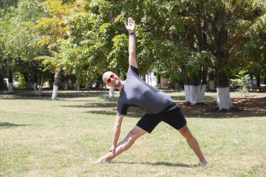 Parkta egzersiz eden adam. Gülümseyen beyaz erkek çim üzerinde çekirdek egzersiz yapıyor.