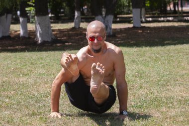 Yeşil parkta yoga yapan genç bir adam. Sağlıklı bir yaşam tarzı kavramı