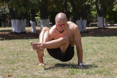 Yeşil parkta yoga yapan genç bir adam. Sağlıklı bir yaşam tarzı kavramı