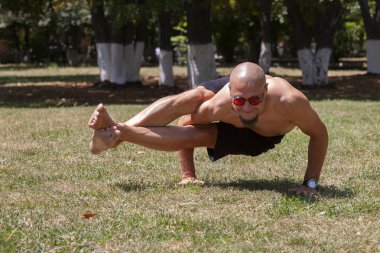 Yeşil parkta yoga yapan genç bir adam. Sağlıklı bir yaşam tarzı kavramı