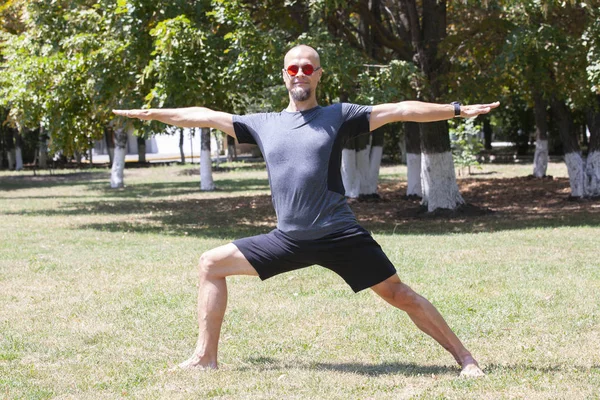 Un uomo che si allena nel parco. Sorridente maschio caucasico facendo core allenamento su erba . — Foto Stock