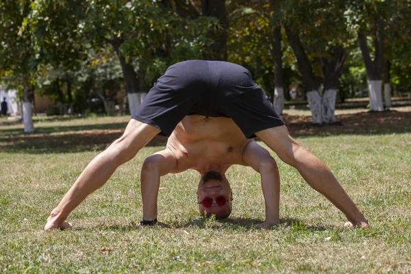 A young man doing yoga in the green park. Concept of a healthy lifestyle