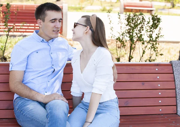 Feliz jovem casal apaixonado sentado em um banco de parque — Fotografia de Stock