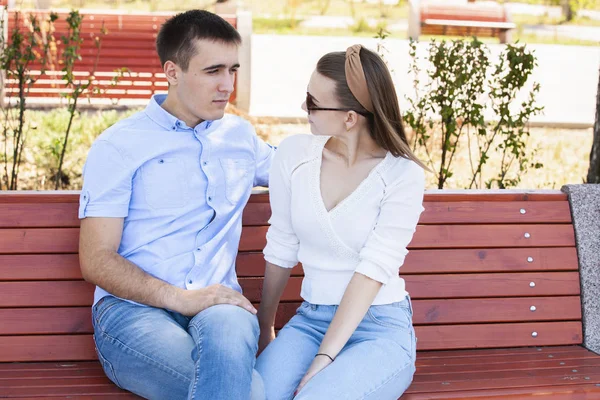 Feliz joven pareja enamorada sentada en un banco del parque — Foto de Stock