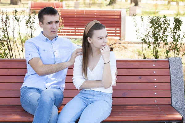 Feliz joven pareja enamorada sentada en un banco del parque — Foto de Stock