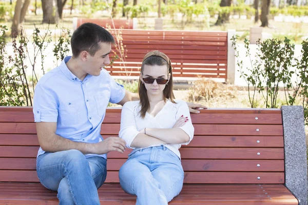 Šťastný mladý pár v lásce sedící na lavičce v parku — Stock fotografie