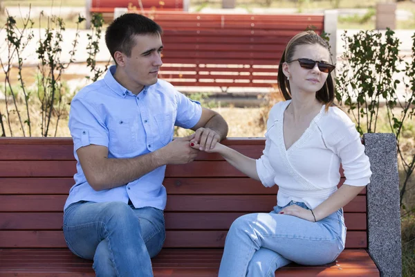 Счастливая молодая влюбленная пара сидит на скамейке в парке — стоковое фото