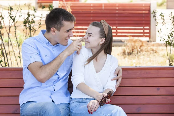 Šťastný mladý pár v lásce sedící na lavičce v parku — Stock fotografie