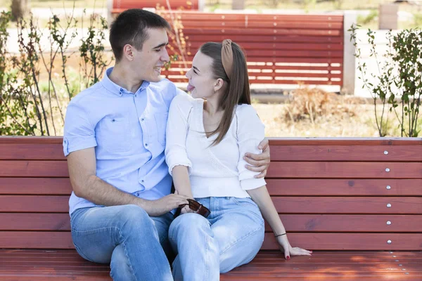 Hermosa pareja joven sentada en un banco en el parque — Foto de Stock