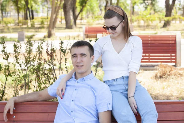 Belo jovem casal sentado em um banco no parque — Fotografia de Stock