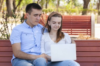 bir dizüstü bilgisayar açık havada kullanarak ve mutlu görünümlü Çift.