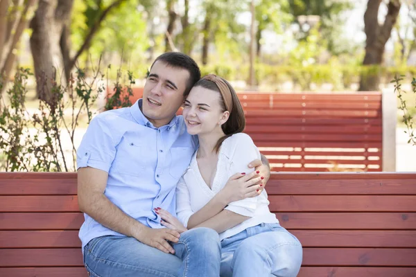 Joven pareja sentado en banco en parque. — Foto de Stock