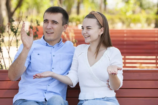 Young couple sitting on bench in park. — Stock Photo, Image