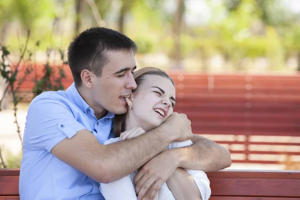 Joven pareja sentado en banco en parque. — Foto de Stock