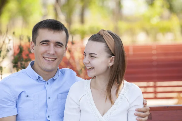 Jovem casal sentado no banco no parque. — Fotografia de Stock