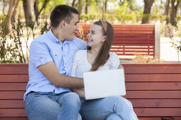 Pareja usando un ordenador portátil al aire libre y mirando feliz . — Foto de Stock