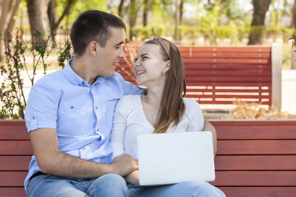 Pareja usando un ordenador portátil al aire libre y mirando feliz . — Foto de Stock