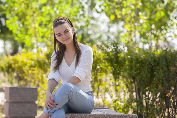 Joven hermosa mujer sentado en banco en parque . — Foto de Stock