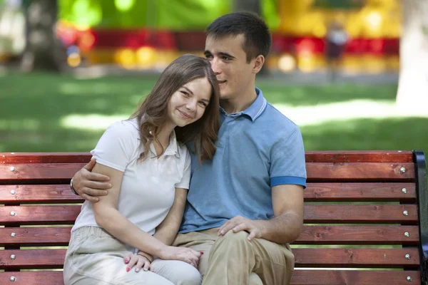 Gelukkige jonge paar verliefd op een bankje zitten en kijken naar camera — Stockfoto