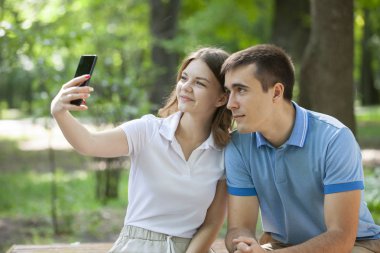 Çift bir parkta bir bankta oturan bir akıllı telefon medya paylaşımı.