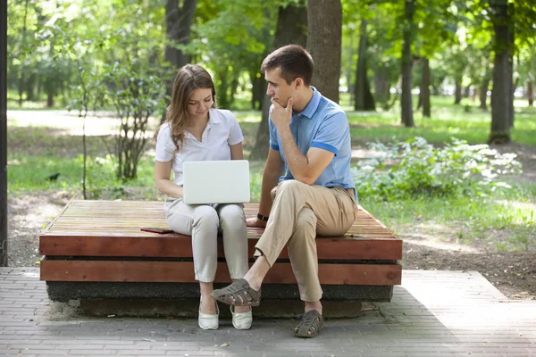 Ein Kerl und ein Mädchen lesen an einem heißen Sommertag in einem Stadtpark ein Buch. — Stockfoto