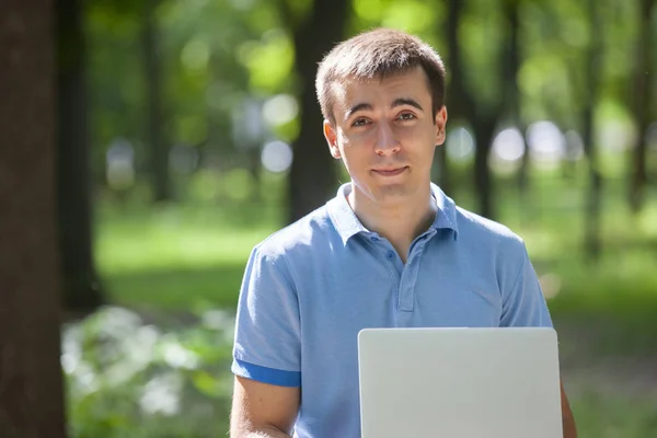 Jonge man met laptop zittend op een houten bankje — Stockfoto