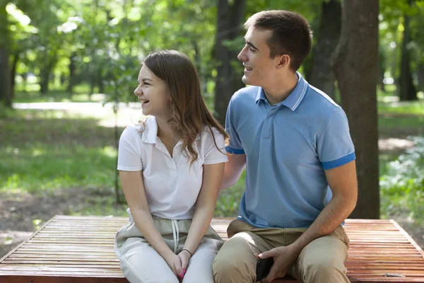 Hermosa pareja joven sentada en un banco en el parque — Foto de Stock