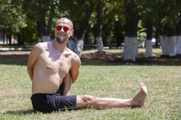 Um jovem fazendo ioga no parque verde. Conceito de um estilo de vida saudável — Fotografia de Stock