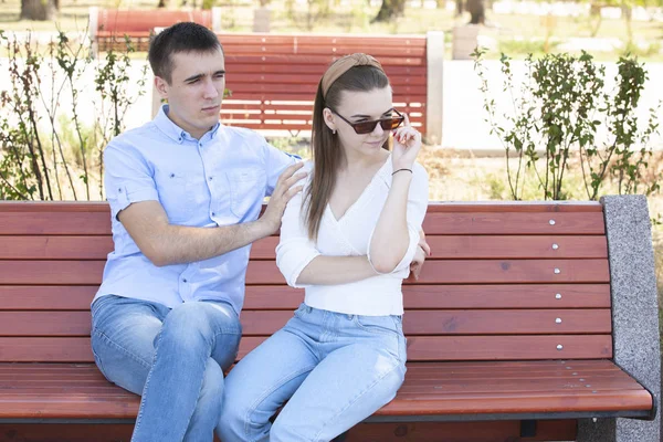 Feliz joven pareja enamorada sentada en un banco del parque — Foto de Stock