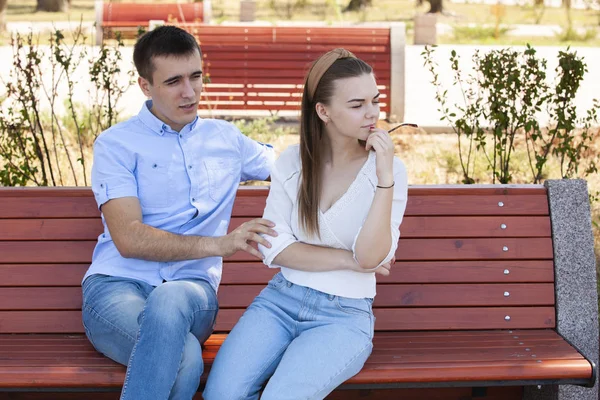 Feliz joven pareja enamorada sentada en un banco del parque — Foto de Stock