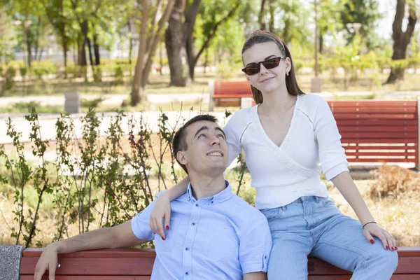 Hermosa pareja joven sentada en un banco en el parque — Foto de Stock