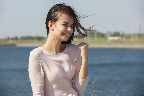 Chica alegre haciendo gesto de disparo de arma. Hermosa joven en casual disfrutando del tiempo libre en el parque de la ciudad, girando, sonriendo y haciendo gestos a la cámara. Concepto de gestos — Foto de Stock