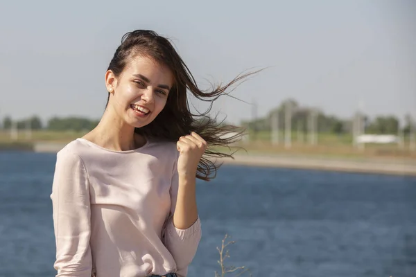 Chica alegre haciendo gesto de disparo de arma. Hermosa joven en casual disfrutando del tiempo libre en el parque de la ciudad, girando, sonriendo y haciendo gestos a la cámara. Concepto de gestos —  Fotos de Stock