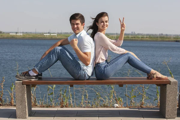 Belo jovem casal sentado em um banco no parque — Fotografia de Stock