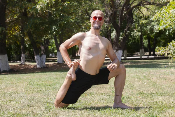 Un giovanotto che fa yoga nel parco verde. Concetto di uno stile di vita sano — Foto Stock